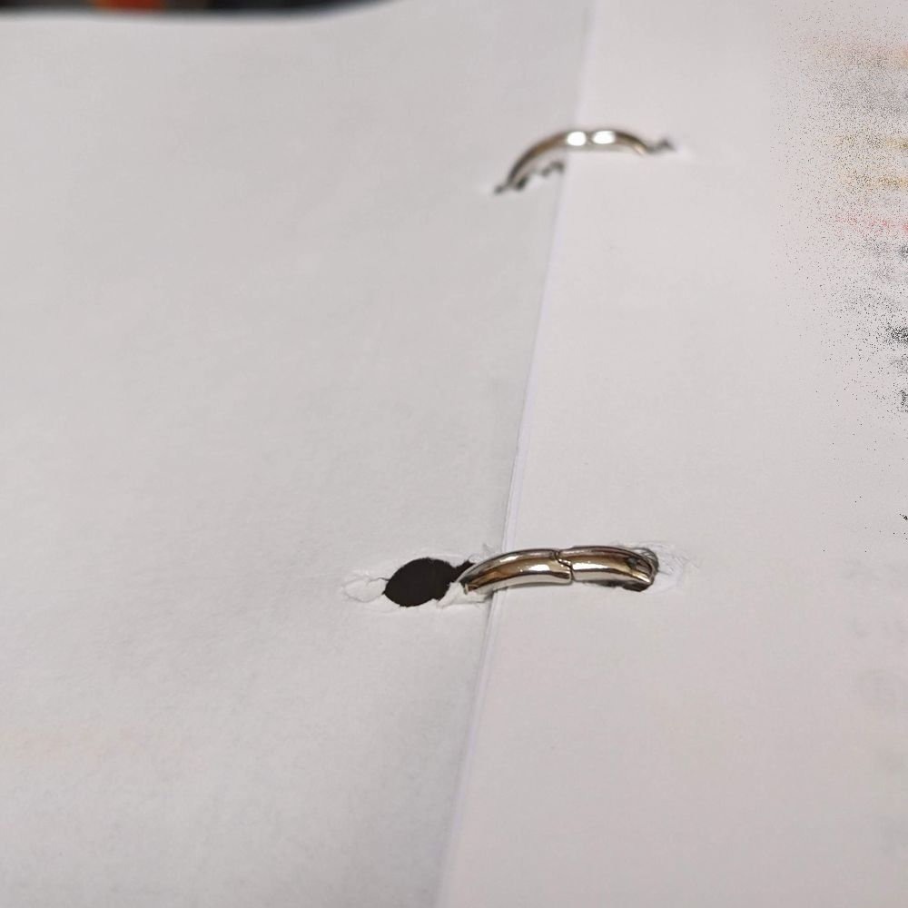 2穴パンチで穴を開けた書類をファイルにとじていて、穴から紙が破れてきた状態